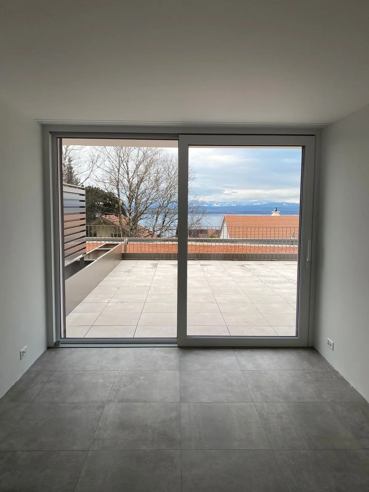 Baie coulissante d'attique ouverte sur la terrasse, vue sur le lac et les Alpes